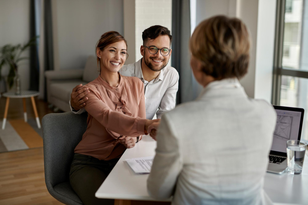 young-happy-couple-shaking-hands-with-insurance-agent-during-meeting-office.jpg