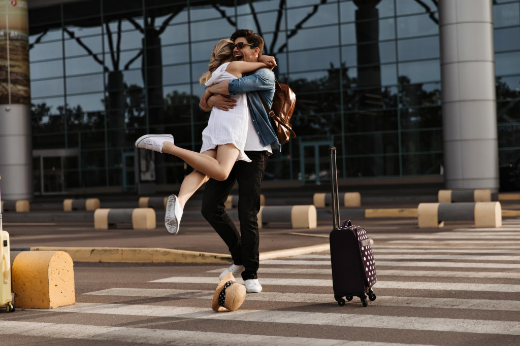 happy-brunette-man-hugs-his-girlfriend-white-dress-woman-meets-boyfriend-airport-tourist-pose-crosswalk-with-suitcase.jpg